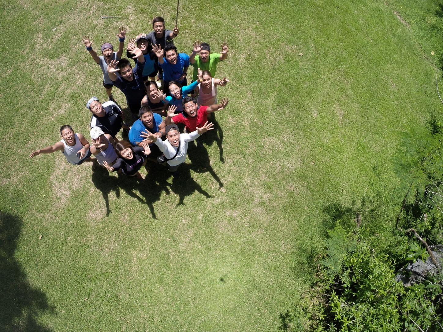 Drone groupfie of new friends waving up from a grass field